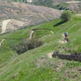a cyclist cruises down narrow bike trail winds between green hills in a sunny valley in loma linda, california
