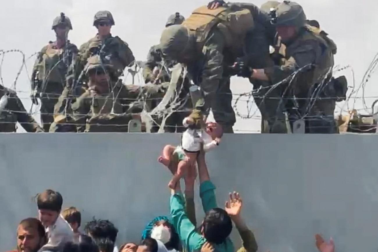 A baby is handed up to the U.S. Army over a perimeter wall at the airport in Kabul, Afghanistan, August 19, 2021 as Afghan civilians and U.S. citizens evacuated the city. 