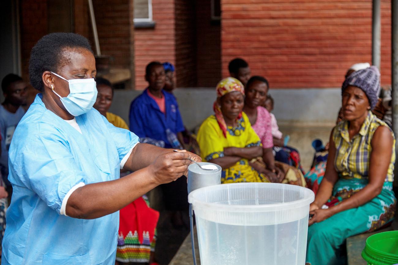 Violett Motta, a health surveillance assistant, mixes chlorine with water to disinfect it at a health centre.