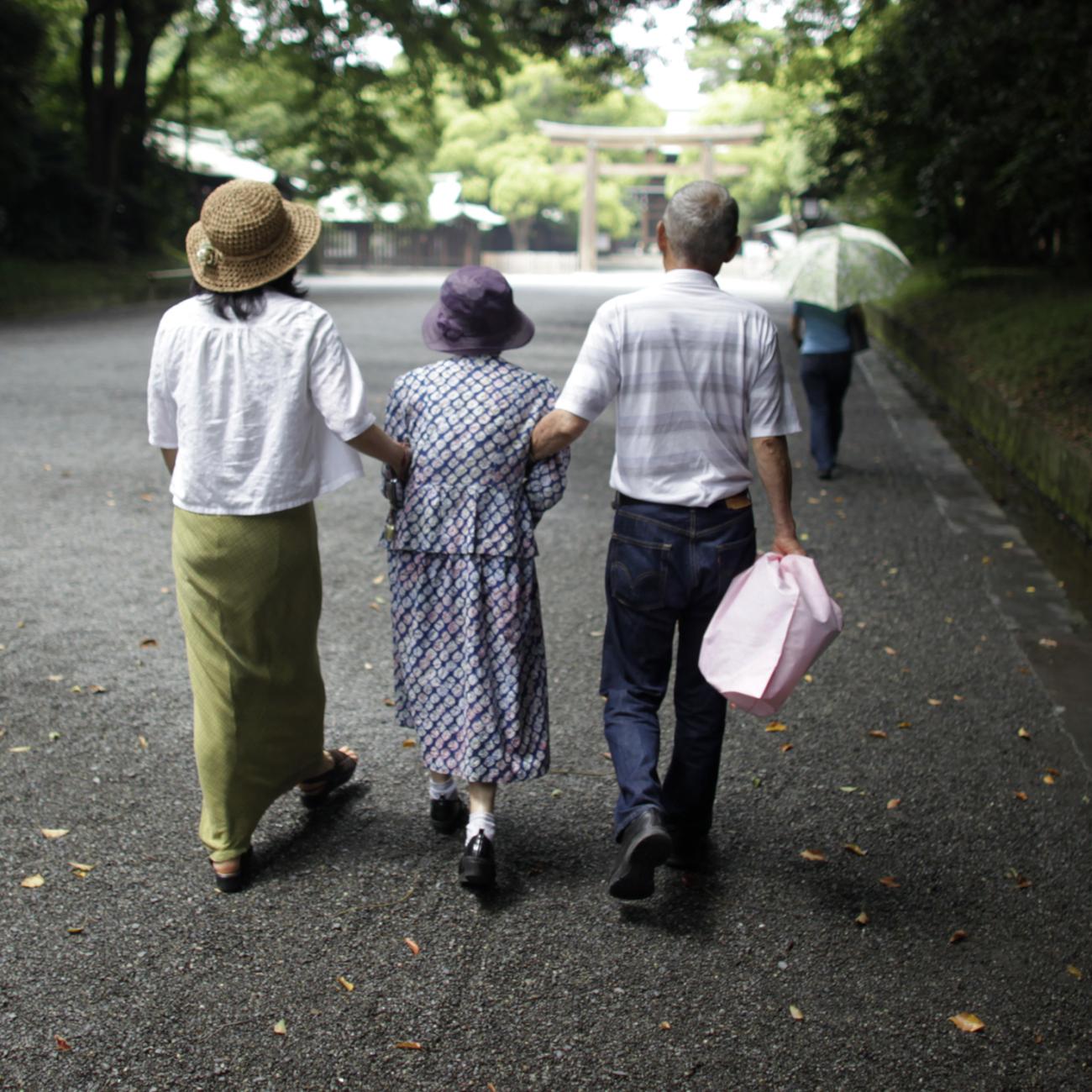 Three people walk down a street with their arms linked.