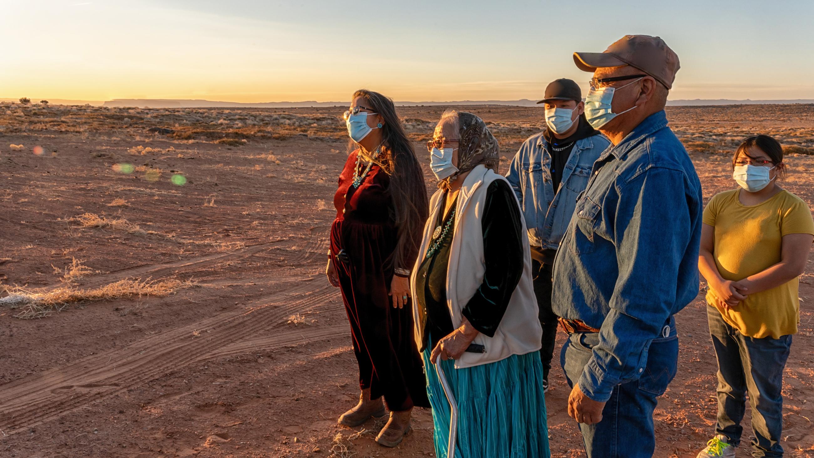 Native American family watching the sunset wearing masks for protection from COVID-19, at Monument Valley Tribal Park, Utah.