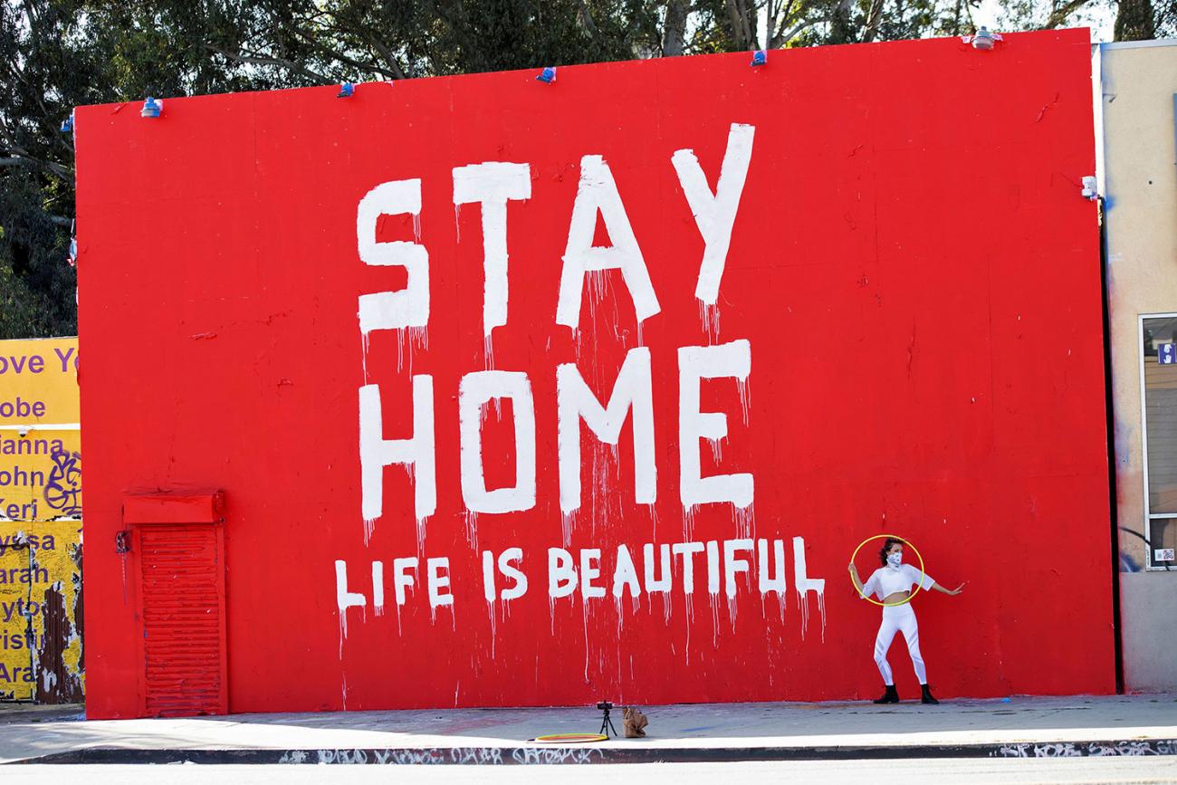 Dance instructor Morgan Jenkins makes a video in Los Angeles, California in front of a mural during the coronavirus pandemic on April 3, 2020. The photo shows a huge striking but crudely hand painted sign that reads "Stay Home / Life is Beautiful." REUTERS/Mario Anzuoni 