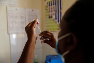 A nurse fills a syringe with malaria vaccine