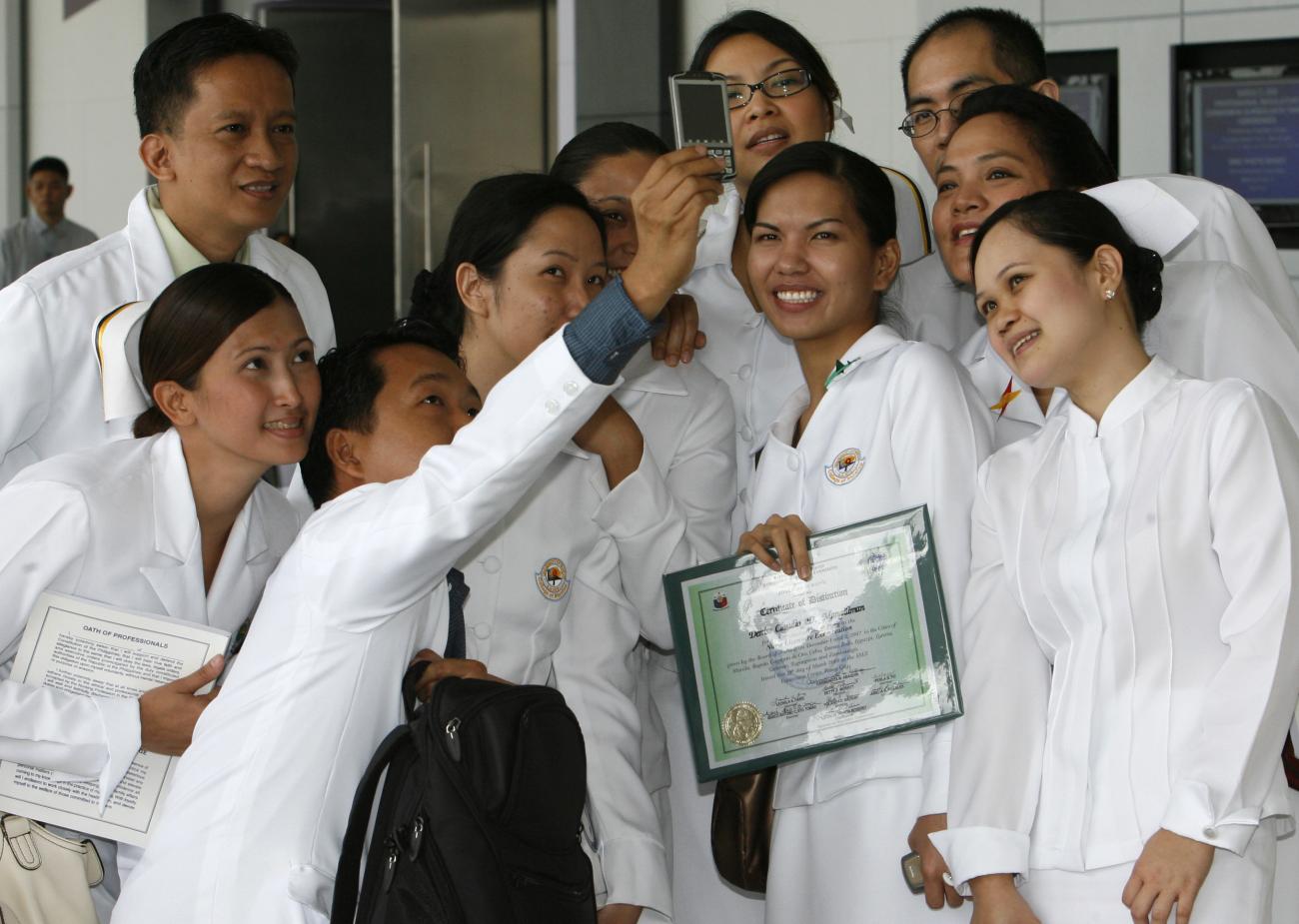Newly-qualified nurses in white coats take a selfie with their diplomas in Manila, Philippines on March 17, 2008.