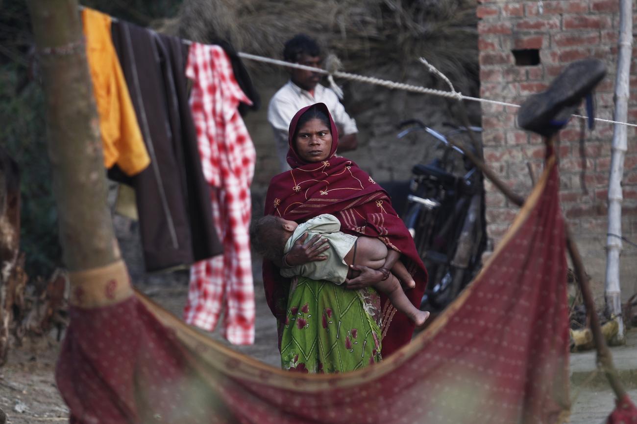 A woman holds her child as she stands outside her house at Dalit village of Bhaddi Kheda in the northern Indian state of Uttar Pradesh January 15, 2012.