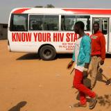 People walk past a bus during an HIV/AIDS awareness campaign on the occasion of World AIDS Day at the Kuchingoro IDPs camp in Abuja, Nigeria, December 1, 2018. 