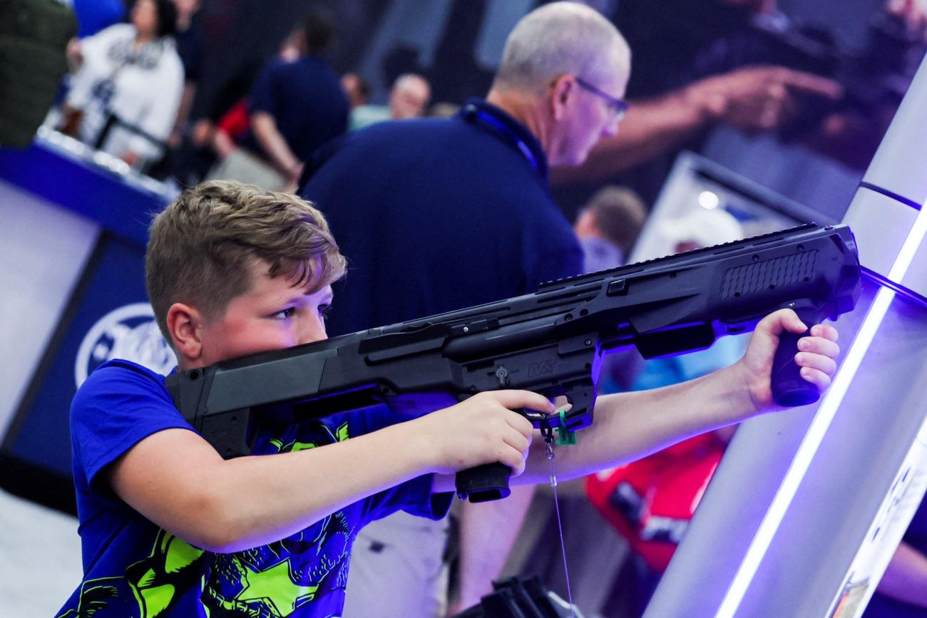 A boy tries out a 12 gauge Smith and Wesson shotgun as people attend the National Rifle Association (NRA) annual convention, in Houston, Texas, on May 28, 2022.