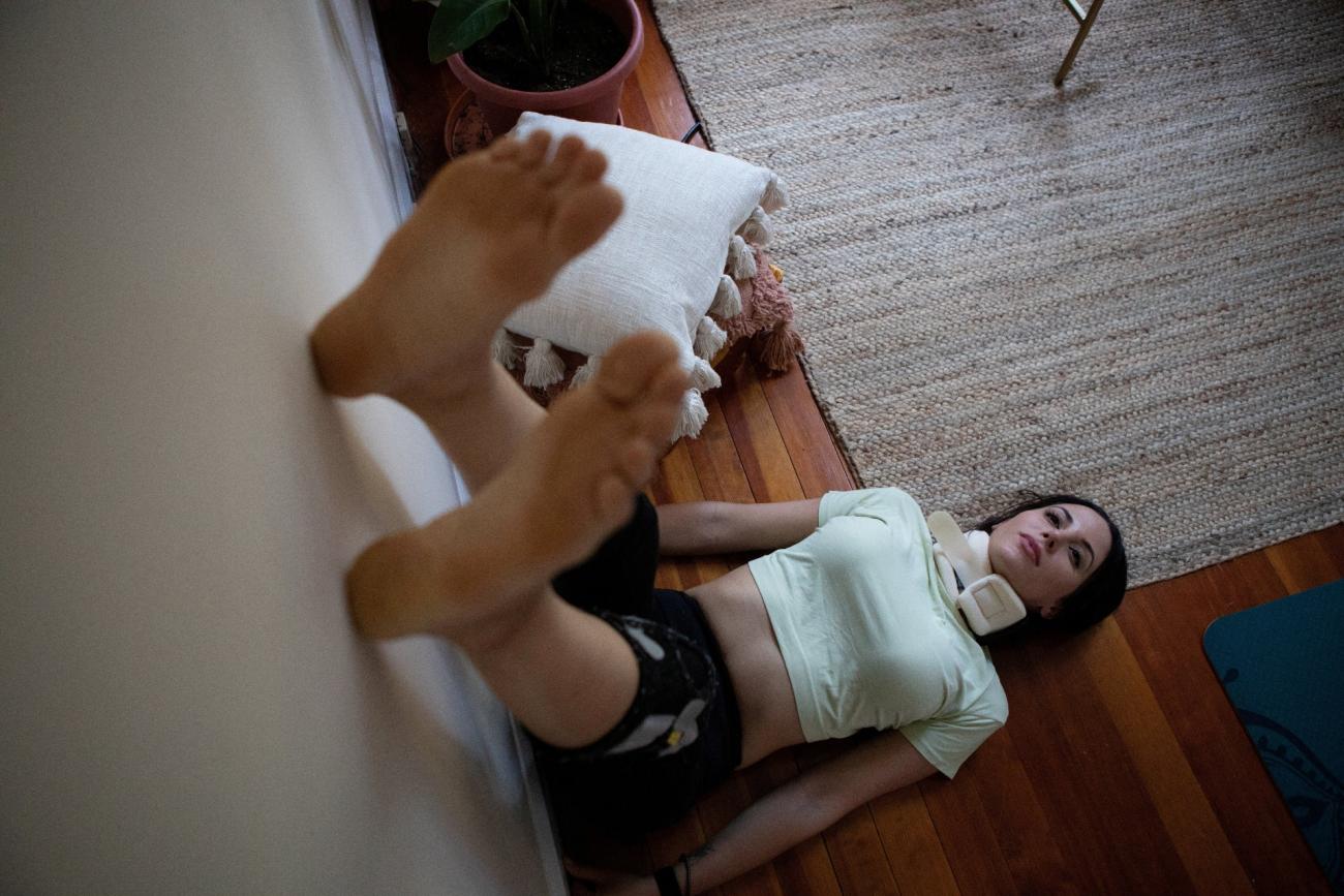 Lauren Nichols, who has long COVID, rests with her feet in the air to get more blood to her head after feeling light-headed in her home in Andover, Massachusetts, on August 3, 2022.