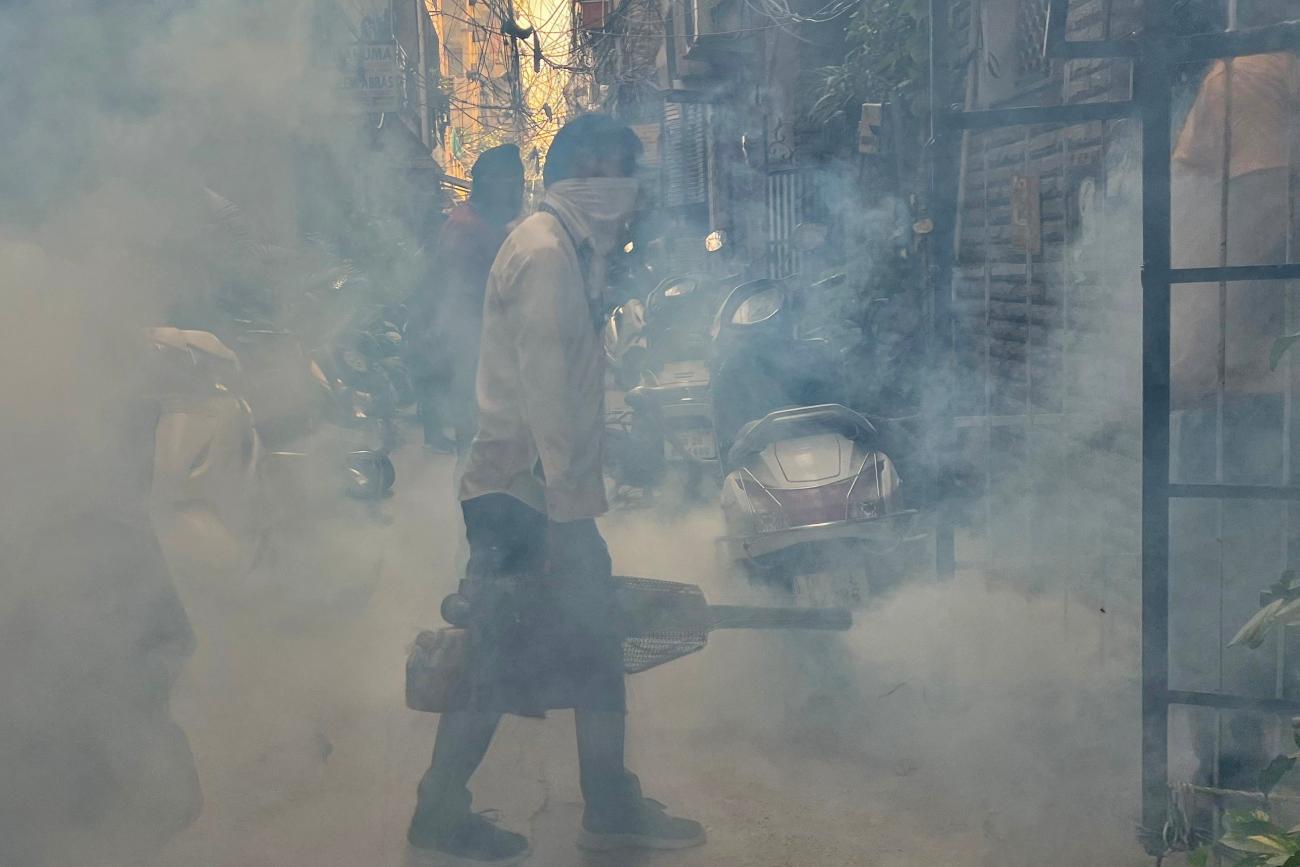 A health worker fumigates an alley in a residential neighbourhood