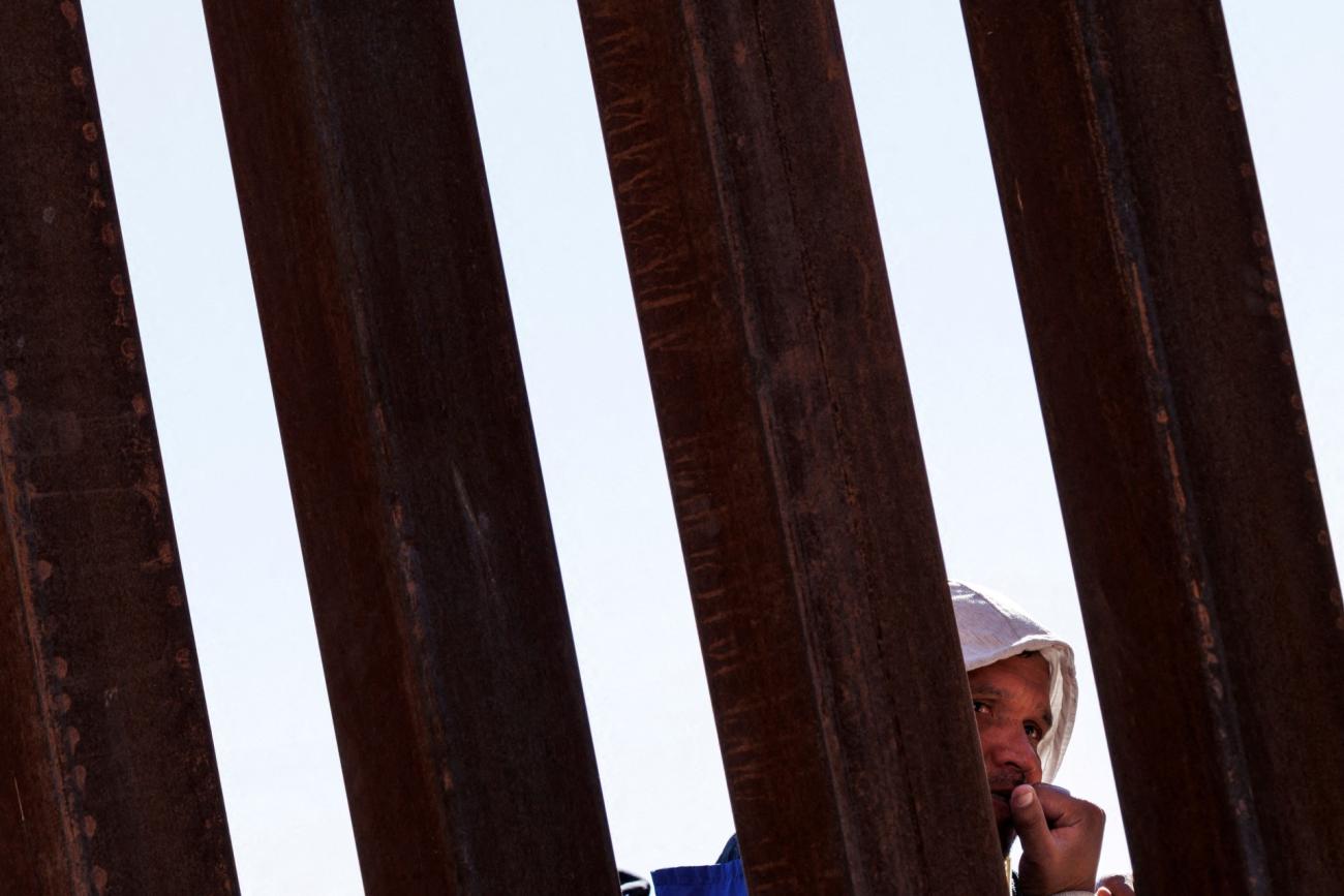 A migrant seeking asylum in the United States waits in line along the border fence at the Rio Bravo River, as seen from El Paso, Texas, on December 22, 2022.its in line along the border fence at the Rio Bravo river, the border between Mexico and the U.S., as seen from El Paso, Texas, on December 22, 2022.