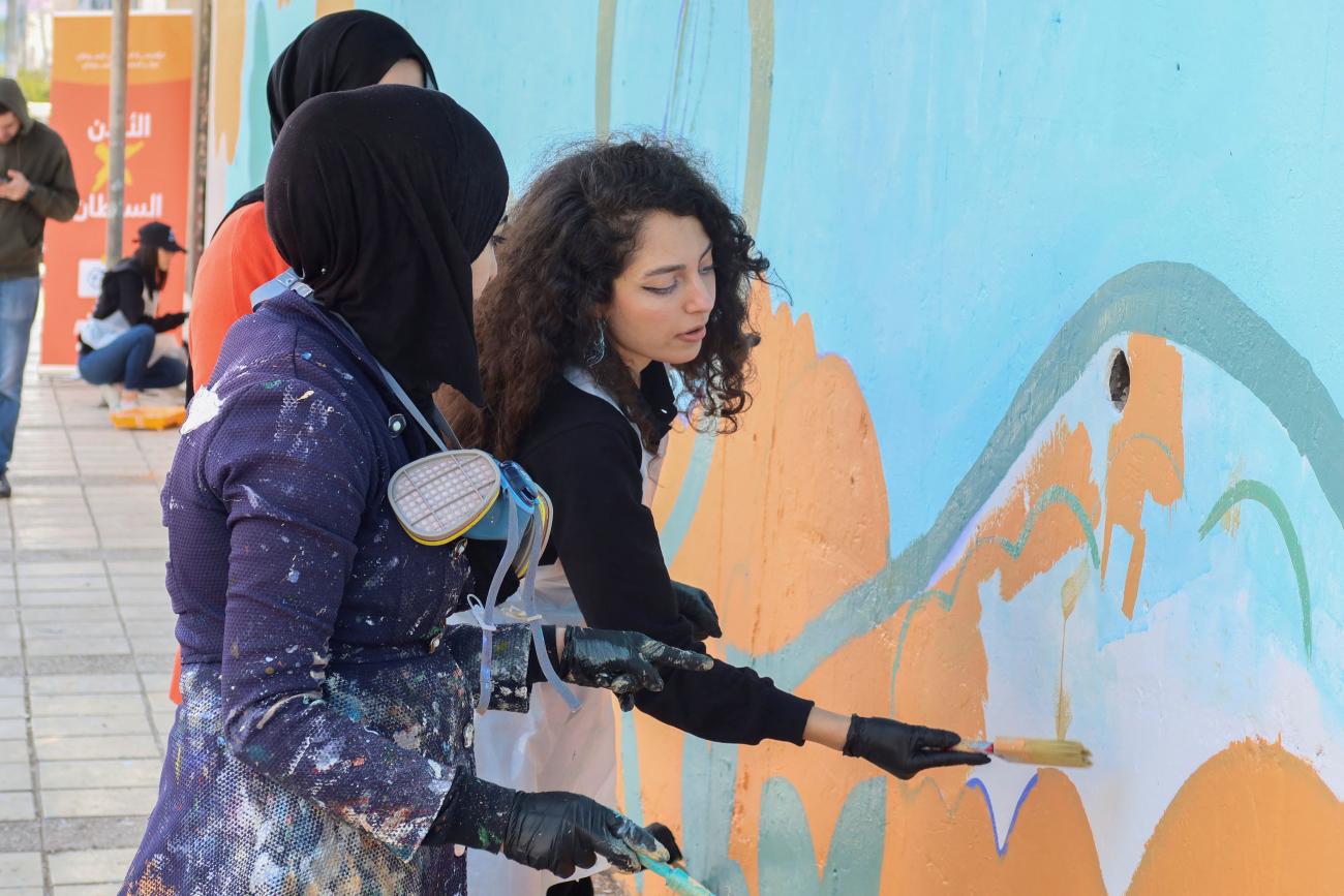 A volunteer paints a mural on a wall in Irbid, Jordan, February 25, 2023.