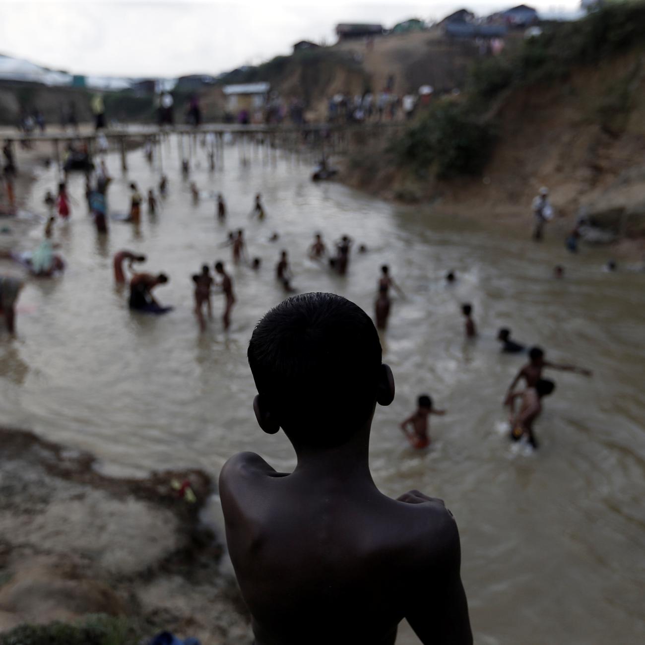 Rohingya refugees swim in a river running through a camp in Cox's Bazar