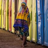 A migrant woman walks past a row of portable toilets at a makeshift border camp along the International Bridge in Del Rio, Texas