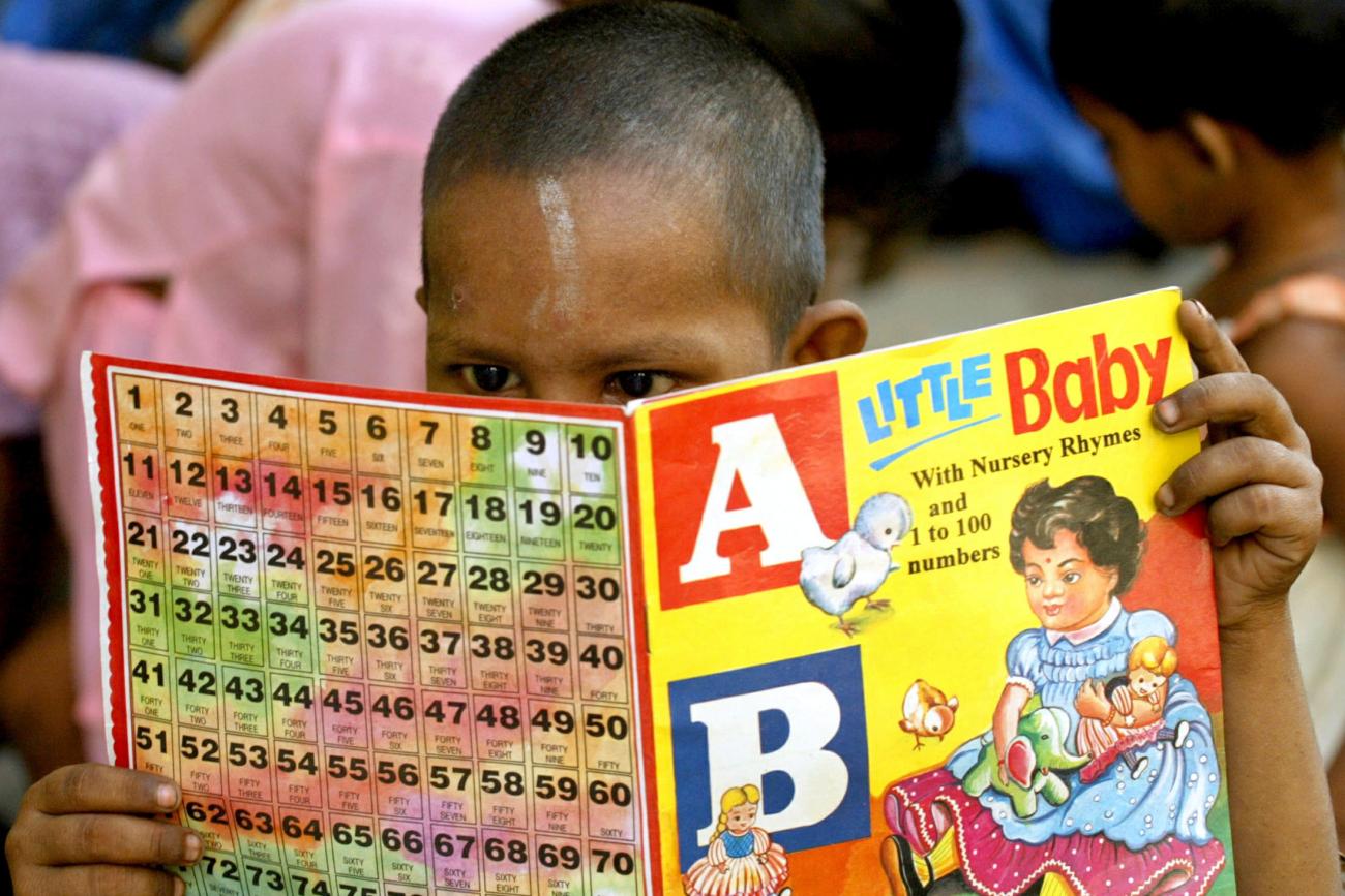a boy with a shaved head reads an ABCs book
