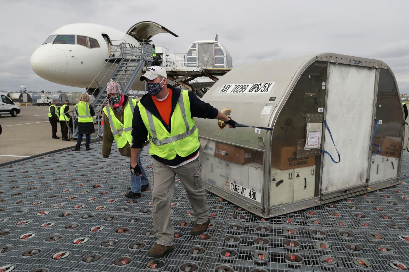 UPS employees move one of two shipping containers of the Pfizer COVID-19 vaccine on ramp at Louisville Muhammad Ali International Airport in Louisville, Kentucky, December 13, 2020.