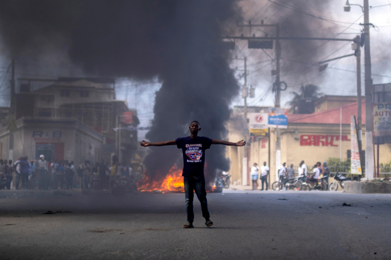 A man stands in front of a burning barricade during a protest against the assassination of Haitian President Jovenel Moise in Cap-Haitien, Haiti on July 22, 2021.
